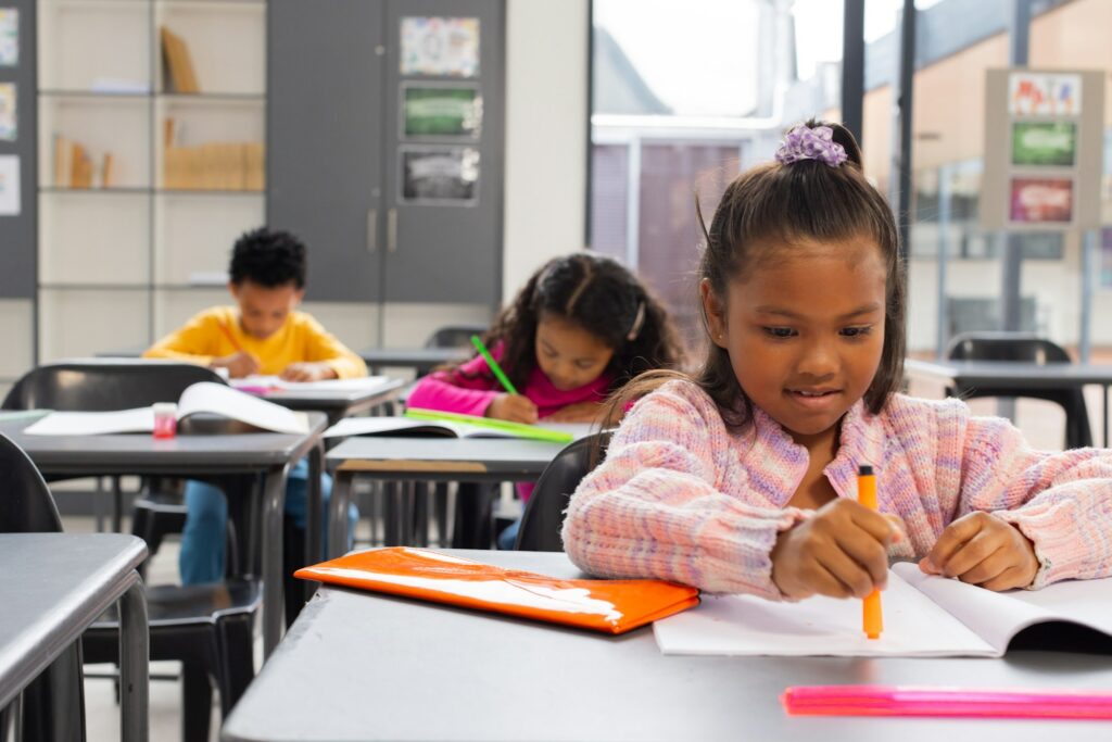 Diverse school children focused on their schoolwork in a school classroom with copy space