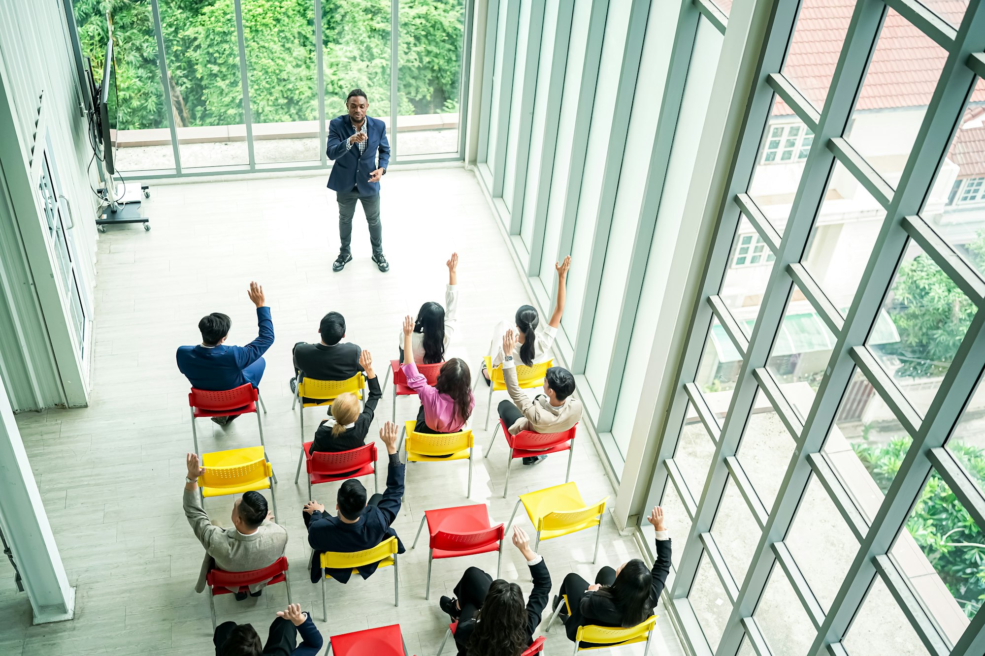 Raised up hands of large group in seminar class room to agree with speaker at conference seminar